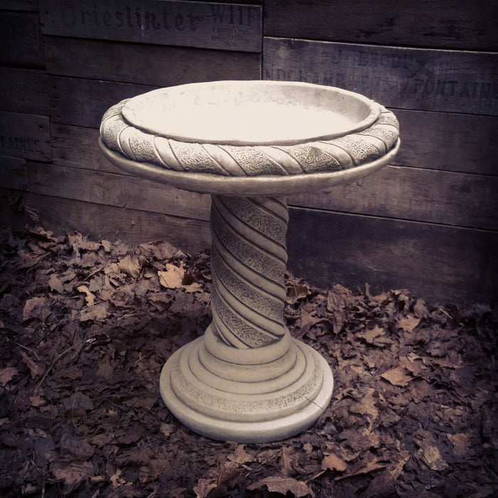 decorative spiral metal garden stake ornament in rust finish beside potted plants